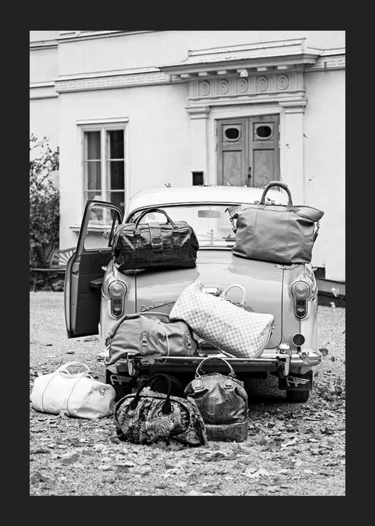 Svartvit fotokonst med gammal bil och resväskor utanför hus-12