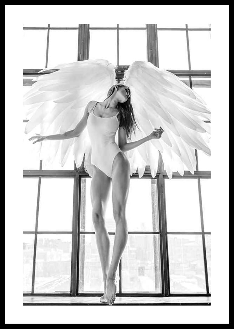 Black and white photo of woman with angel wings by large window-12