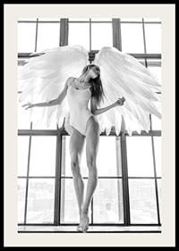 Black and white photo of woman with angel wings by large window-2