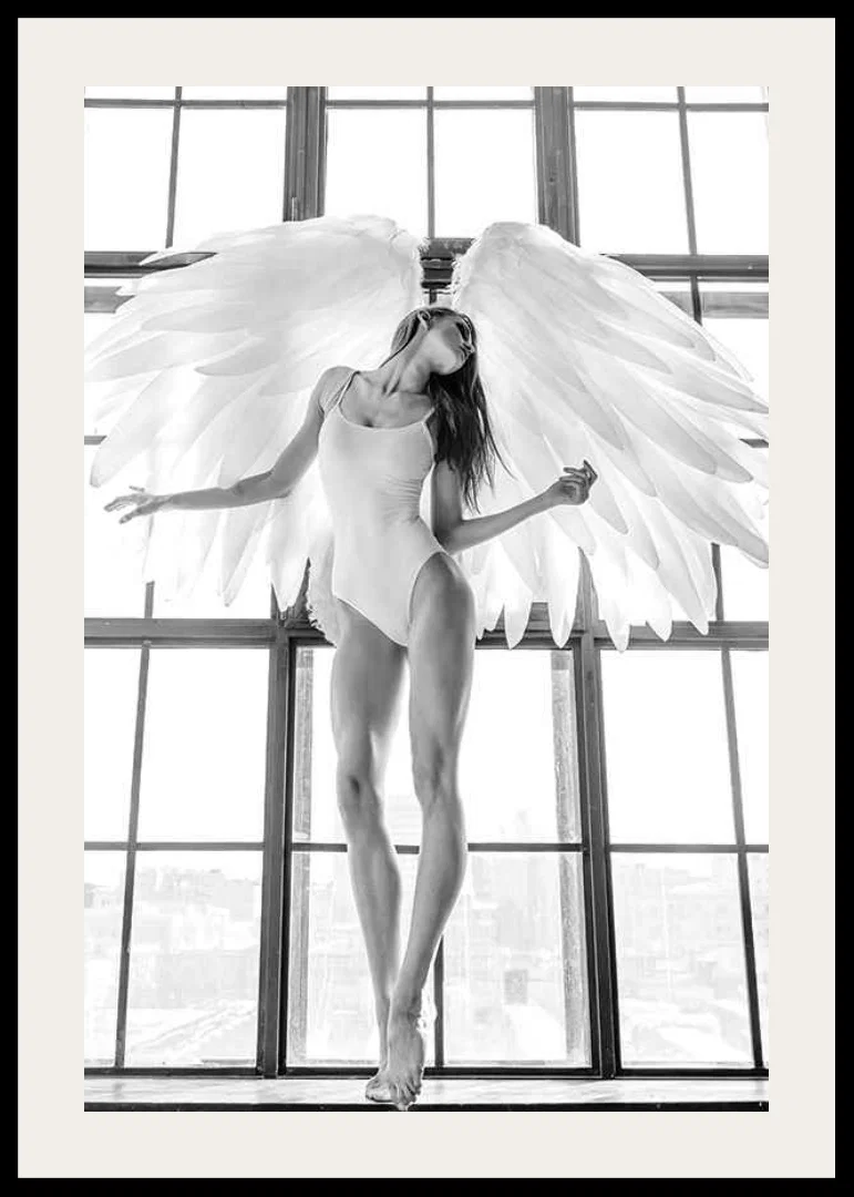 Black and white photo of woman with angel wings by large window-12