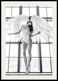 Foto in bianco e nero di una donna con ali d'angelo vicino a una grande finestra-2