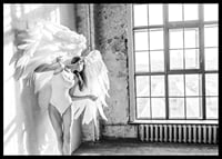 Black and white photo of woman with large angel wings by window-6