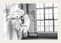 Čiernobiela fotografia ženy s veľkými anjelskými krídlami pri okne-3