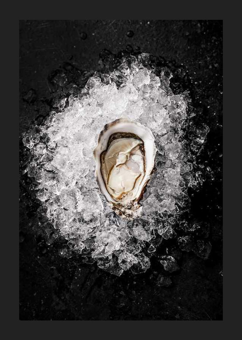Primer plano de una ostra abierta sobre hielo picado contra un fondo negro-12