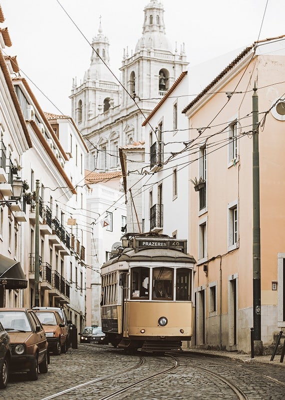 Photograph of yellow tram on narrow cobblestone street in Lisbon-12