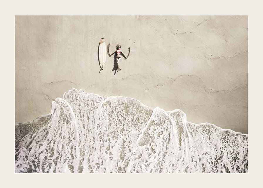 Ylhäältä päin nainen surffilaudan kanssa hiekkarannalla-12