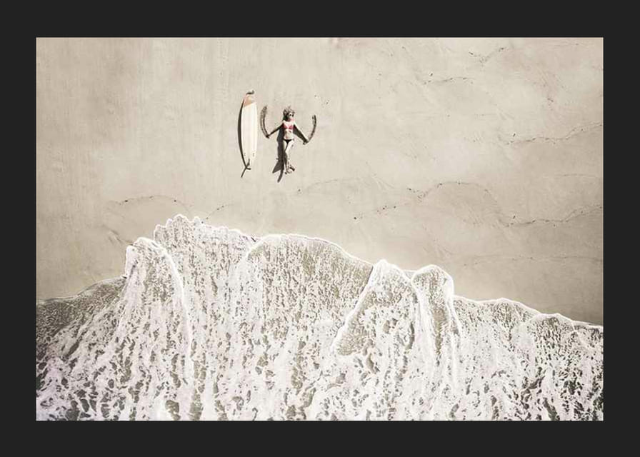 Ylhäältä päin nainen surffilaudan kanssa hiekkarannalla-12