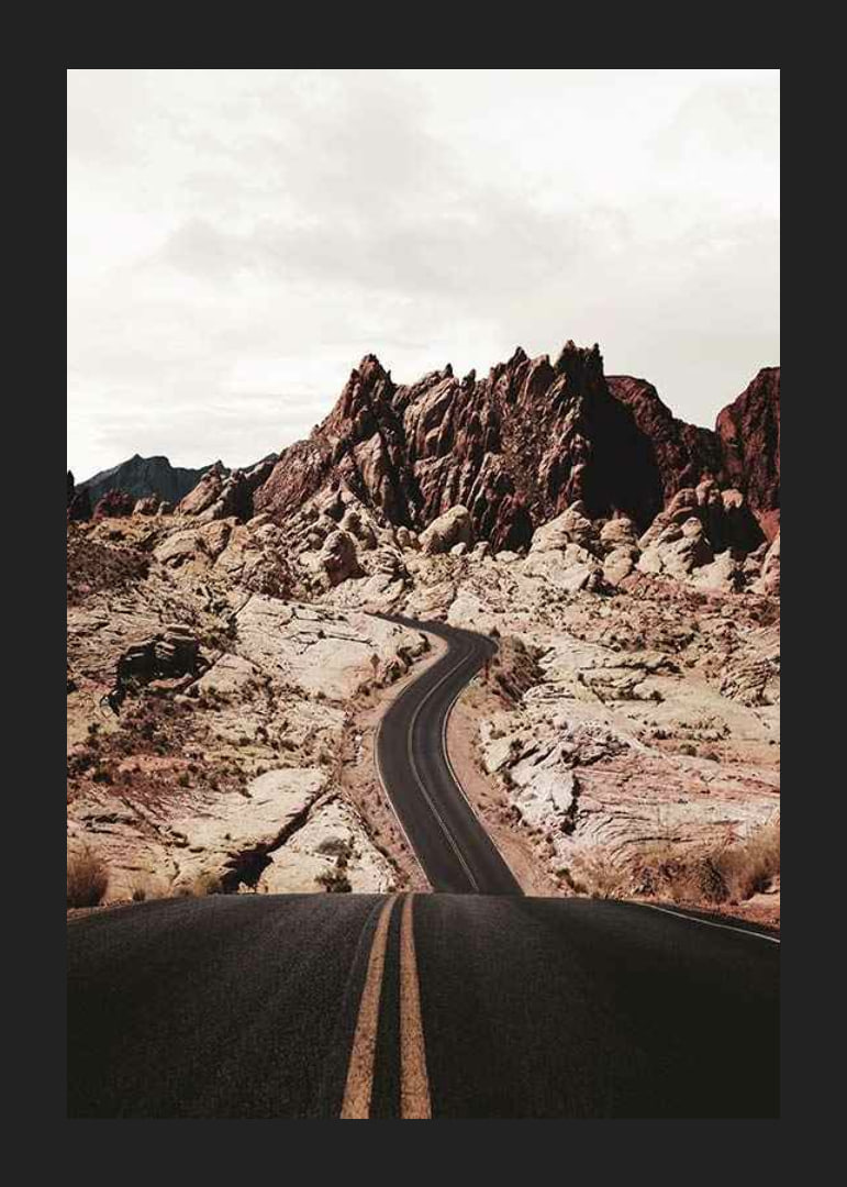 Asphalt road through reddish-brown rocks in desert landscape-12