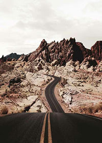 Asphalt road through reddish-brown rocks in desert landscape-7