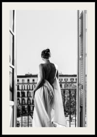 Black and white photo of woman in white dress at open balcony door-2