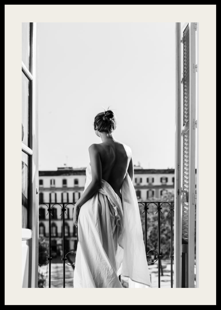 Black and white photo of woman in white dress at open balcony door-12
