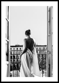 Black and white photo of woman in white dress at open balcony door-0