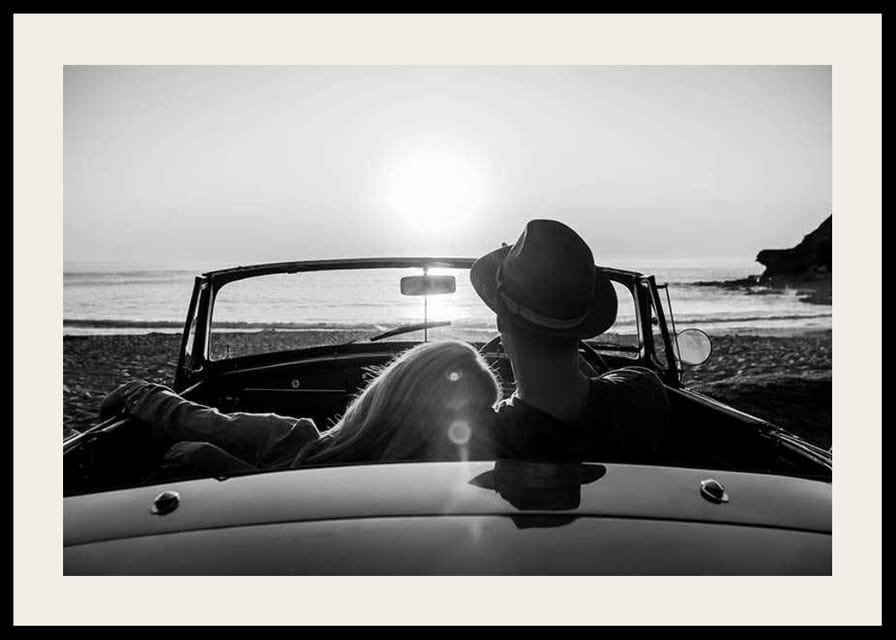 Fekete-fehér fotó egy párról kabrióban naplementekor az óceán felett-12