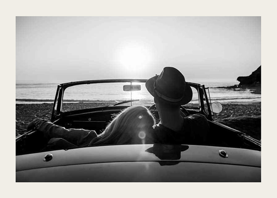 Black and white photography of couple in convertible at sunset over ocean-12