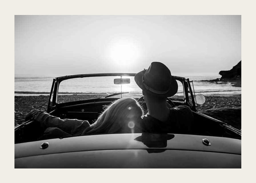 Fekete-fehér fotó egy párról kabrióban naplementekor az óceán felett-12