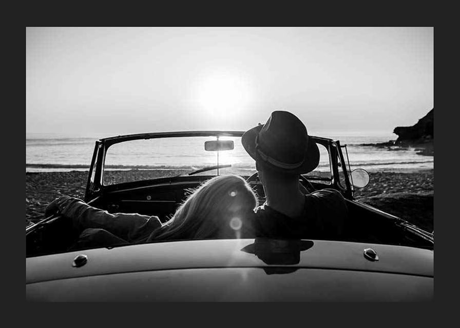 Black and white photography of couple in convertible at sunset over ocean-12