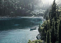 Photograph of lone boat on turquoise water at forested bay-7