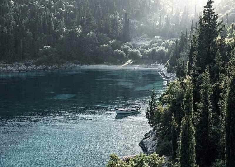 Photograph of lone boat on turquoise water at forested bay-12