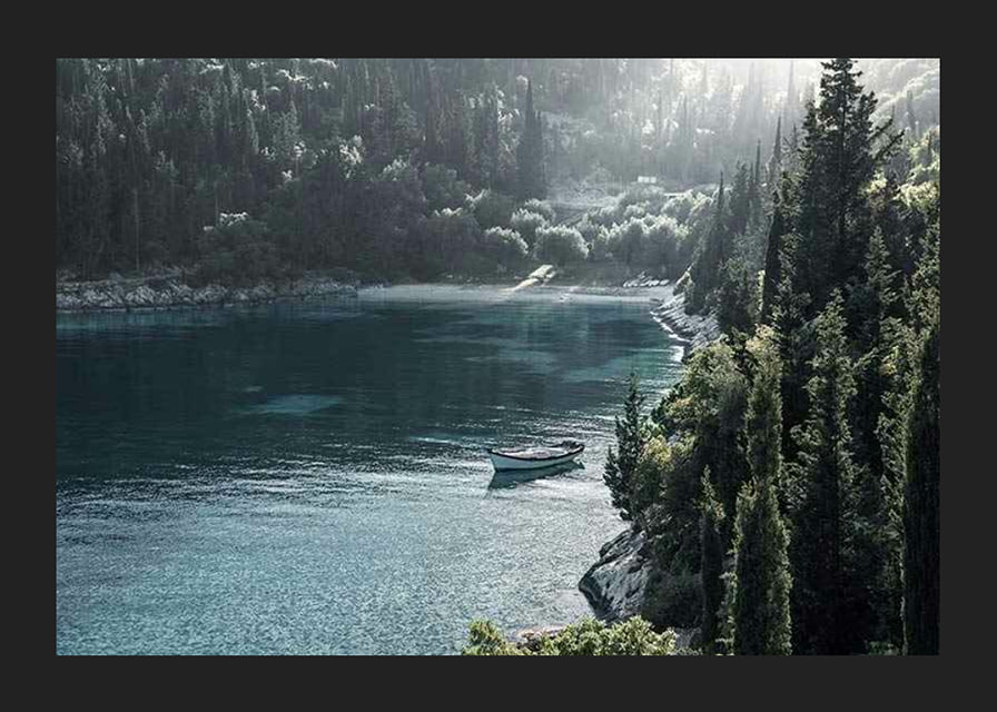 Photograph of lone boat on turquoise water at forested bay-12