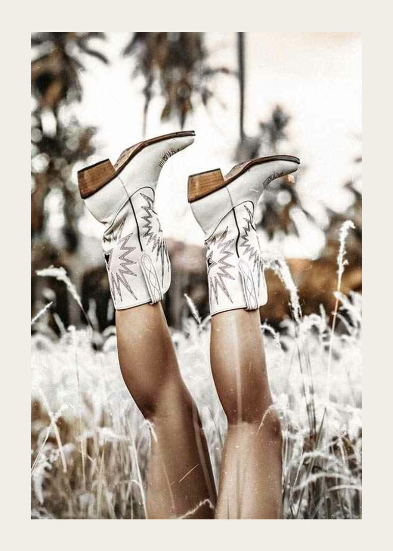 Foto van benen met witte cowboylaarzen in grasveld-12