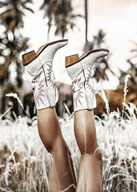 Photograph of legs with white cowboy boots in grass field-7