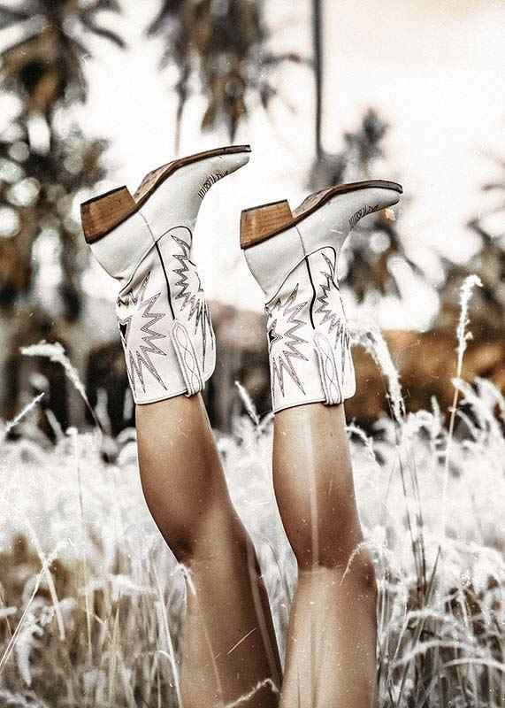 Photograph of legs with white cowboy boots in grass field-12