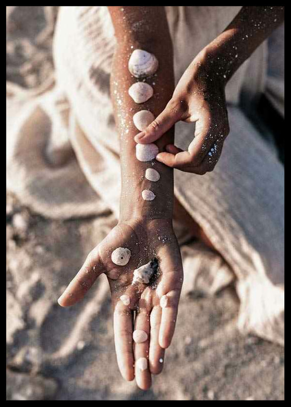 Photograph of arm with white shells on sunny beach-12