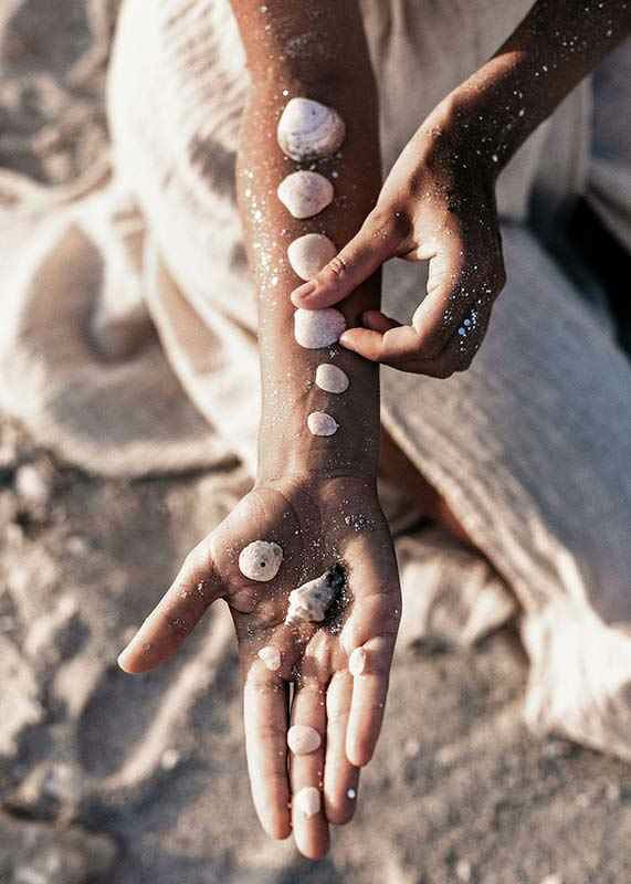 Photograph of arm with white shells on sunny beach-12
