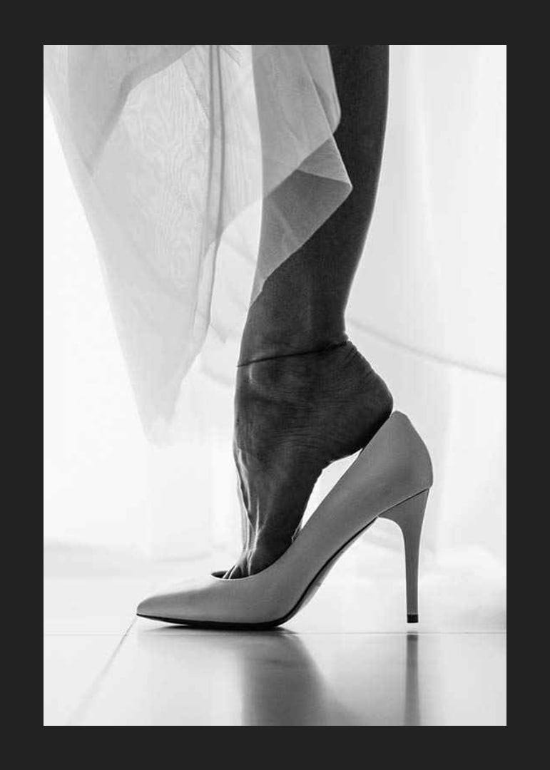 Black and white photograph of woman's feet put in white high heels-12
