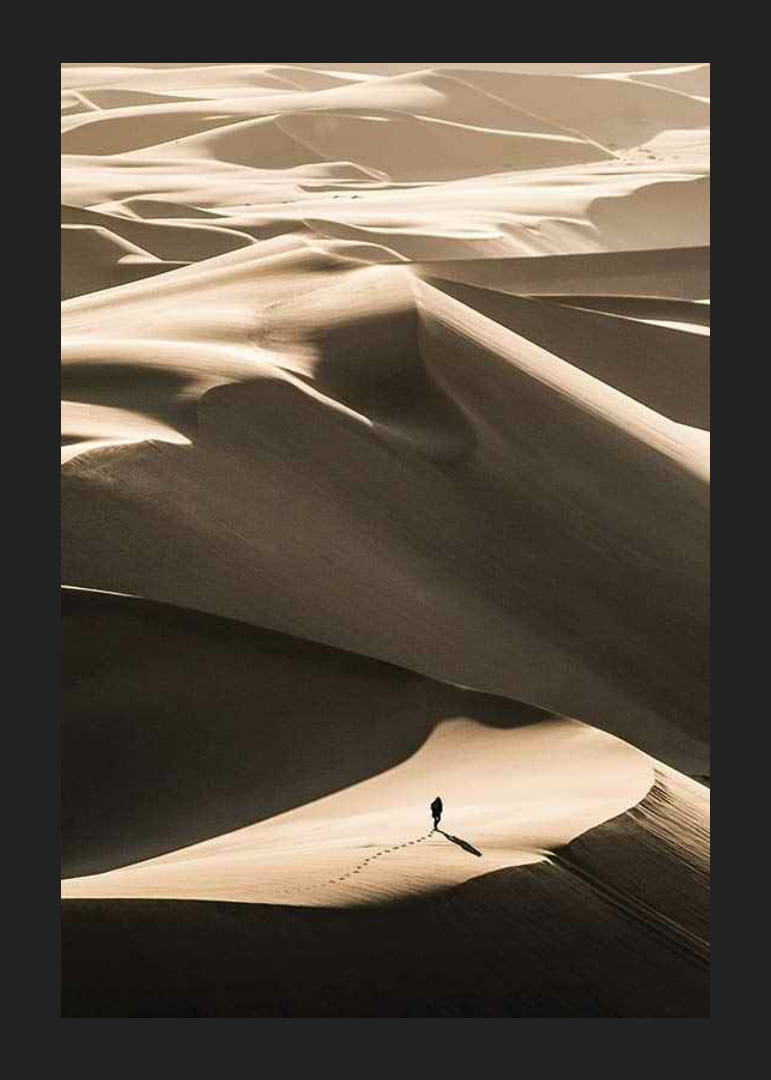 Photographie d'une personne seule sur des dunes de sable ondulantes dans le désert-12