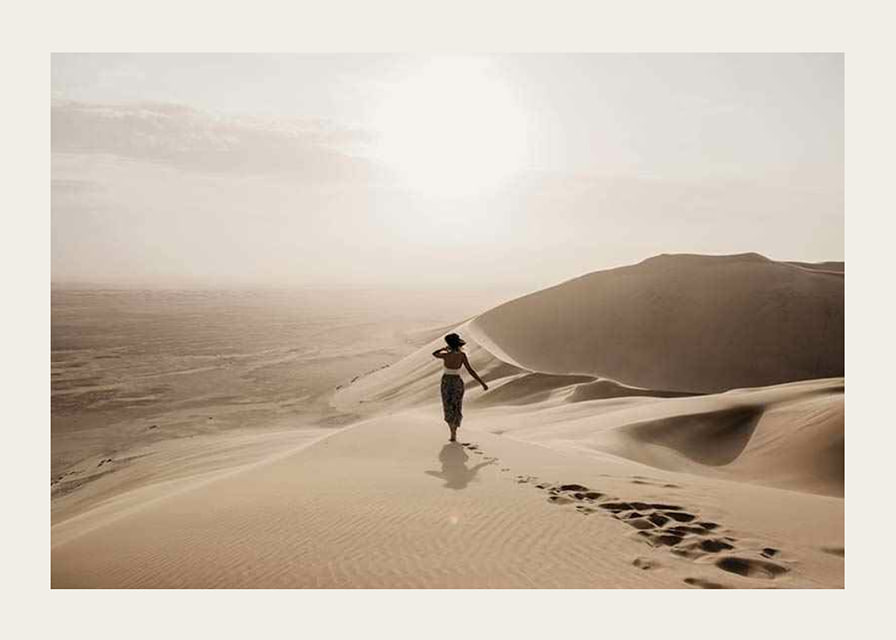 Photographic woman in hat on sand dunes in hot desert environment-12