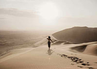 Photographic woman in hat on sand dunes in hot desert environment-7