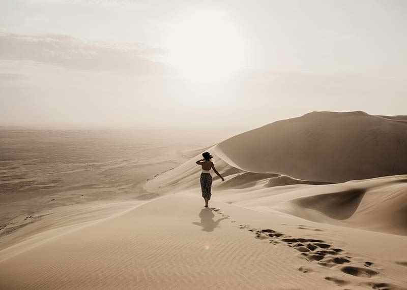 Photographic woman in hat on sand dunes in hot desert environment-12