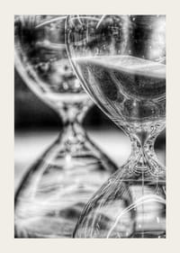 Schwarz-weiße Nahaufnahme von zwei Sanduhren mit fließendem Sand-3