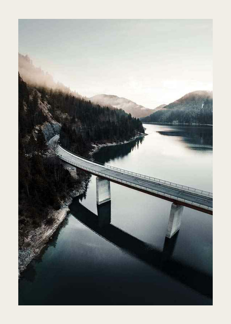 Photographic bridge over calm lake with forested mountains-12