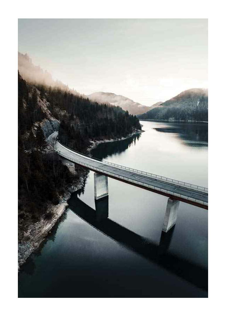 Photographic bridge over calm lake with forested mountains-12