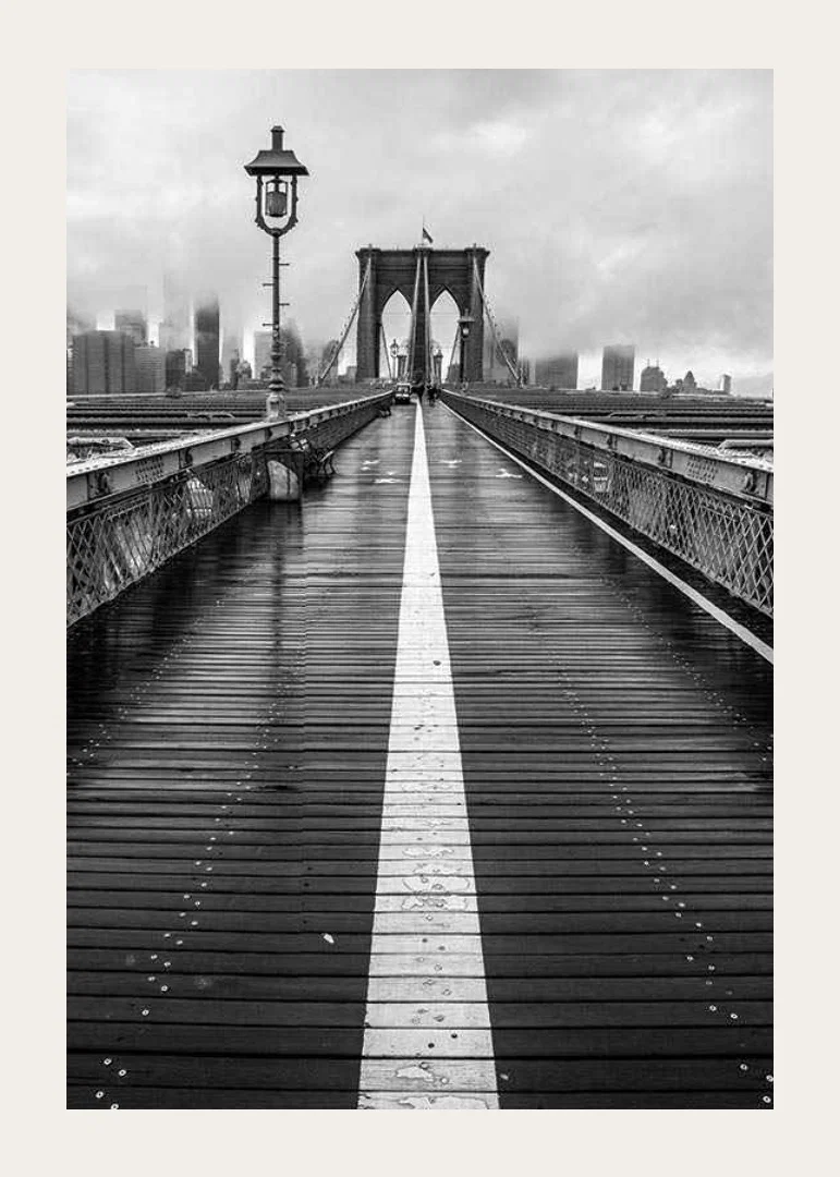 Black and white photograph of Brooklyn Bridge with wet wooden surface-12