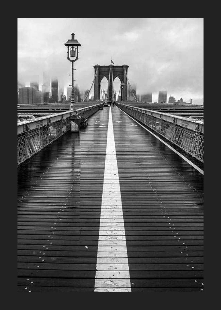 Black and white photograph of Brooklyn Bridge with wet wooden surface-12