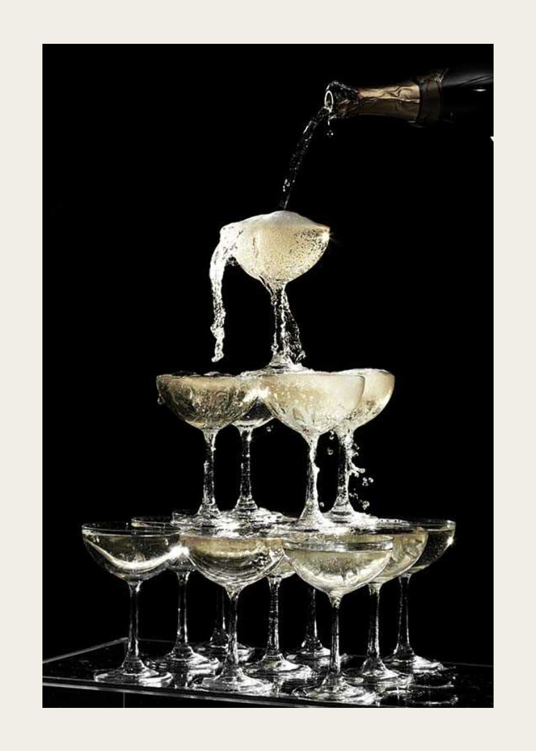 Photograph of champagne tower with flowing bubbles against black background-12