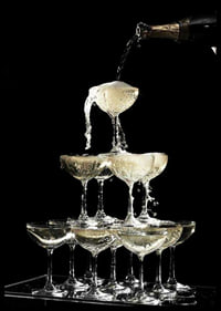 Photograph of champagne tower with flowing bubbles against black background-6