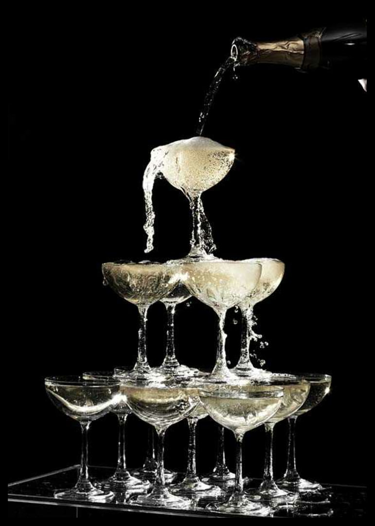 Photograph of champagne tower with flowing bubbles against black background-12