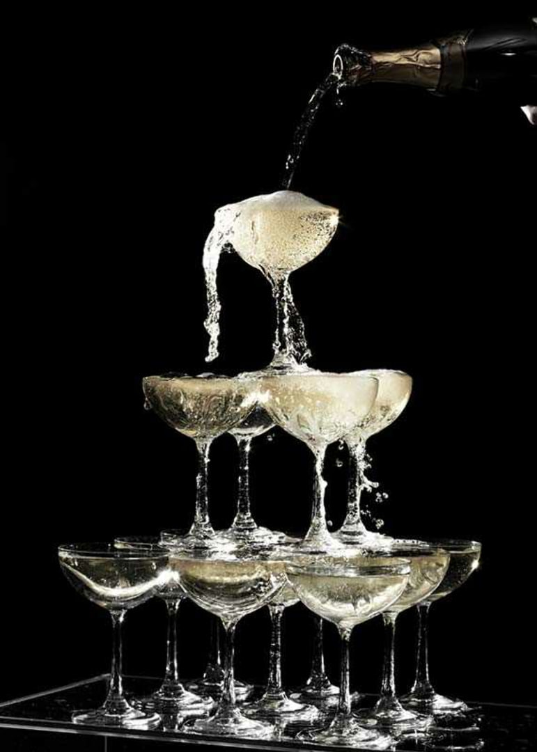 Photograph of champagne tower with flowing bubbles against black background-12