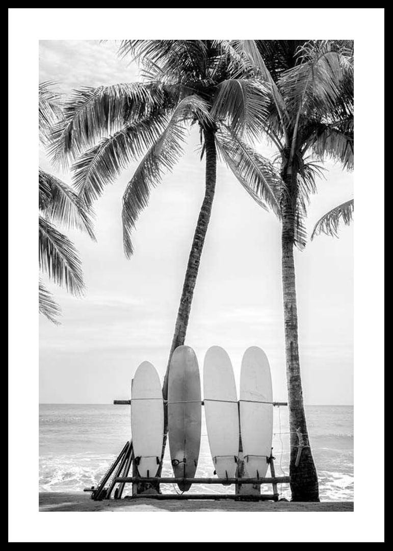 Black and white photo of surfboards against palm trees and ocean-12