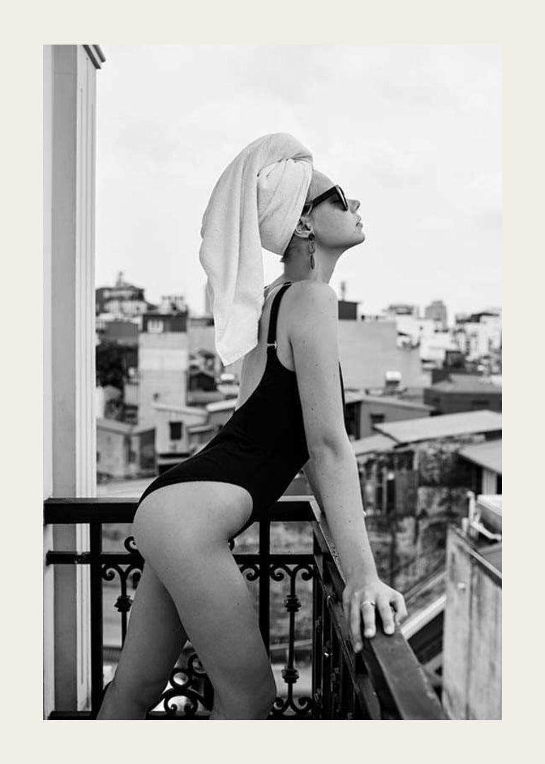 Black and white photograph of woman in swimsuit on balcony-12