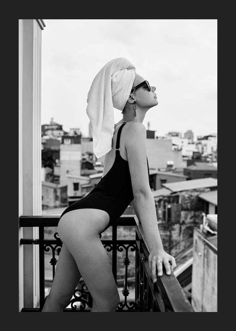 Black and white photograph of woman in swimsuit on balcony-12