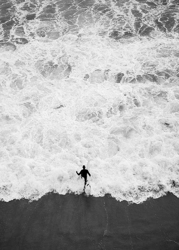 Black and white photo of person running towards wavy sea-12