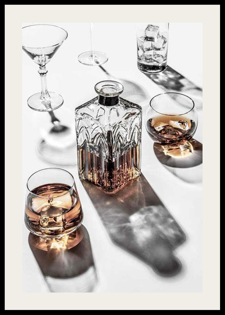 Fotografia di una caraffa di whisky e di un bicchiere con ghiaccio su una superficie chiara-12