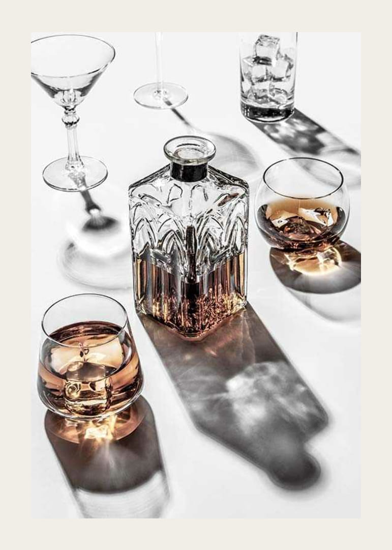 Fotografia di una caraffa di whisky e di un bicchiere con ghiaccio su una superficie chiara-12