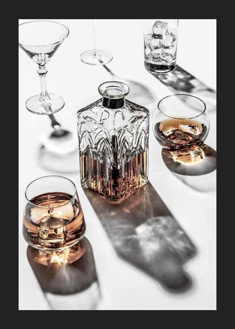 Photograph of whiskey decanter and glass with ice on light surface-12