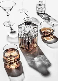 Photograph of whiskey decanter and glass with ice on light surface-7
